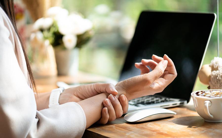 A woman holds her wrist in pain from carpal tunnel syndrome.