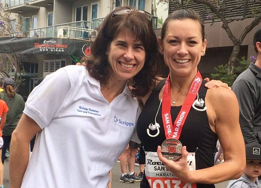A Scripps MD and a diabetic San Diego marathon runner holding her racing medal enjoy a moment together after a marathon.