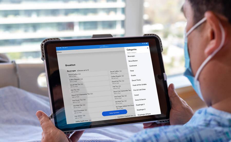 A Scripps Health patient in their hospital room ordering a meal or snack online, illustrating Scripps dining and nutrition options.