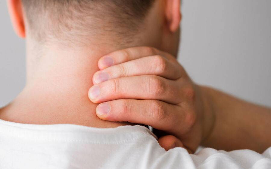 A man in pain grabs his neck; may consider cervical spine fusion in the future.