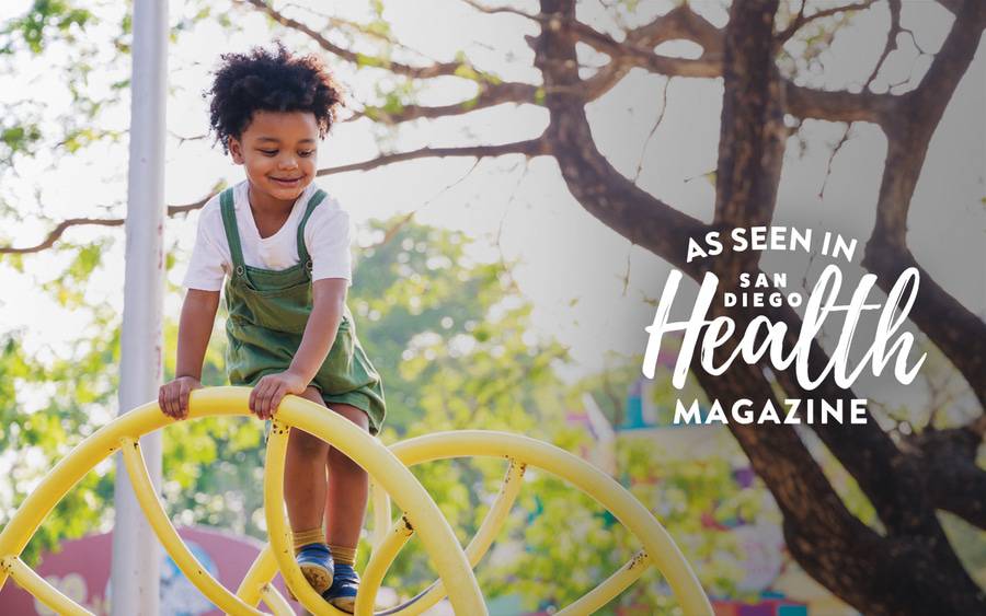 A young child playing on a jungle gym outside in a park.