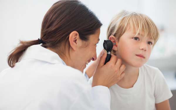 A physician uses a medical instrument to look into the ear of a young child.