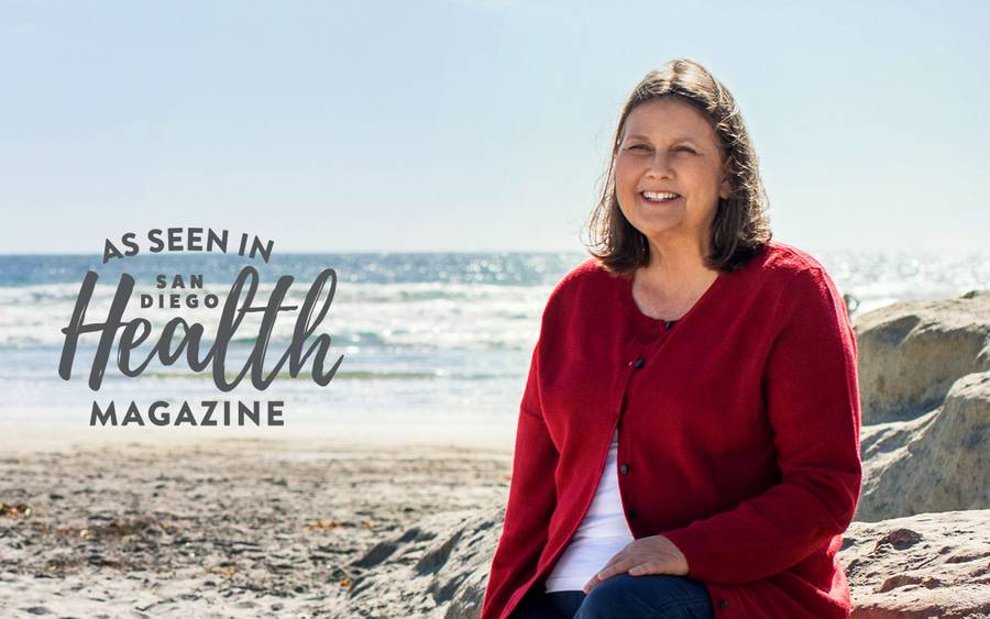 Woman in red cardigan sitting on the beach.