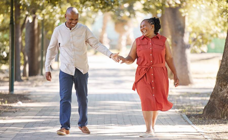 A happy couple smiling and walking holding hands, illustrating the quality of life after having knee replacement surgery.