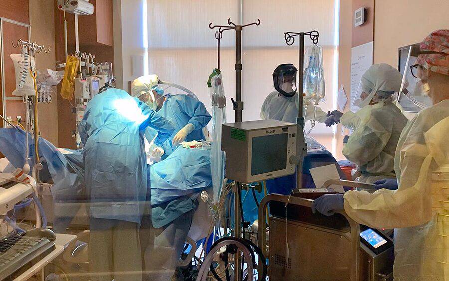 Several Scripps medical professionals administer care to a patient who is critically ill with COVID-19.