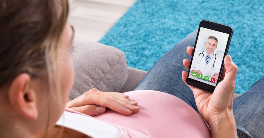A pregnant woman is having a video visit consulataion with a physician.