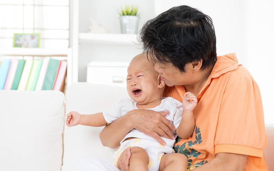 An Asian mother comforts her baby that is experiencing symptoms of croup, a common childhood viral infection that affects the upper airway.