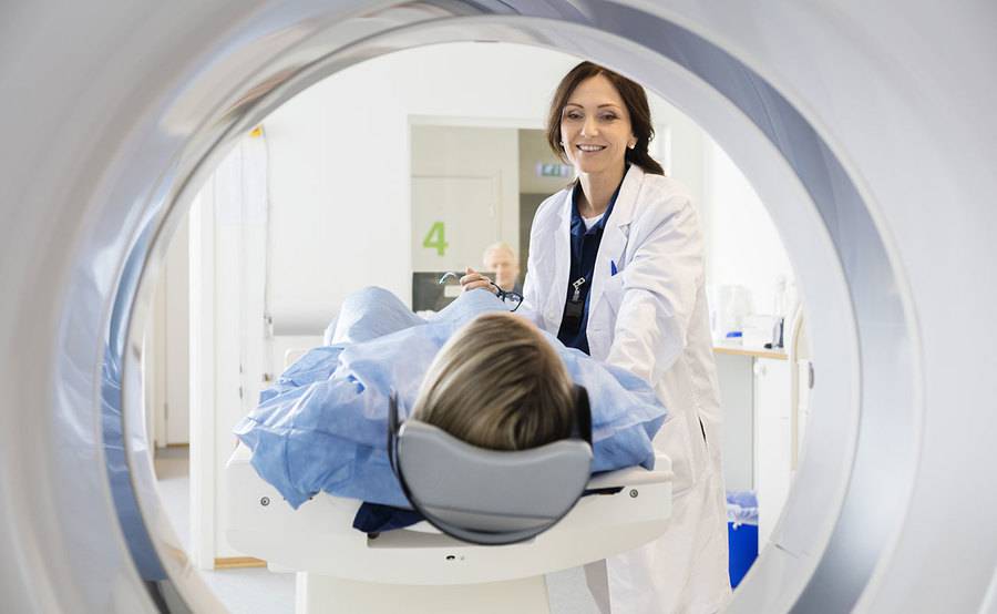 A radiologic technologist prepares a woman for a CT scan, representing a common type of imaging at Scripps Health.