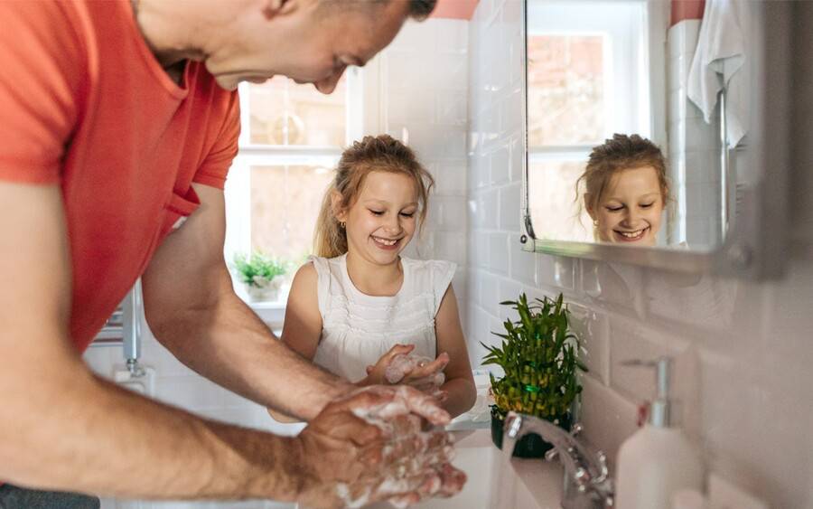 Father and daughter lathering their hands to clean them and protecting against COVID-19 while listening to music.