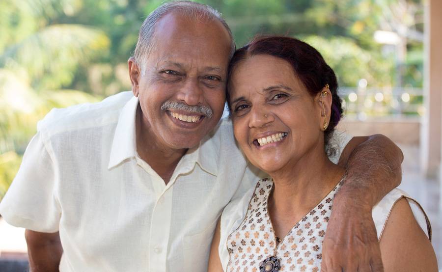 A smiling mature man wraps his arm around his wife, representing the variety of people who need a DEXA bone scan.
