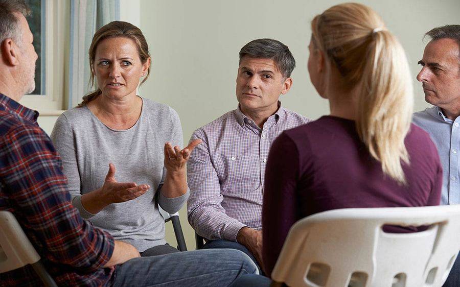 A group of adults sitting in a circle talking and listening