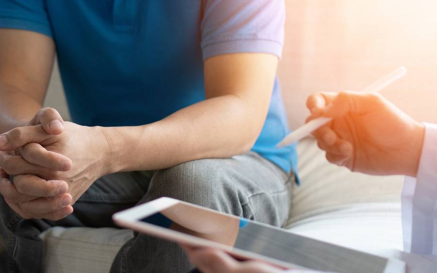 A doctor is utilizing a tablet while speaking to a patient about prostate cancer