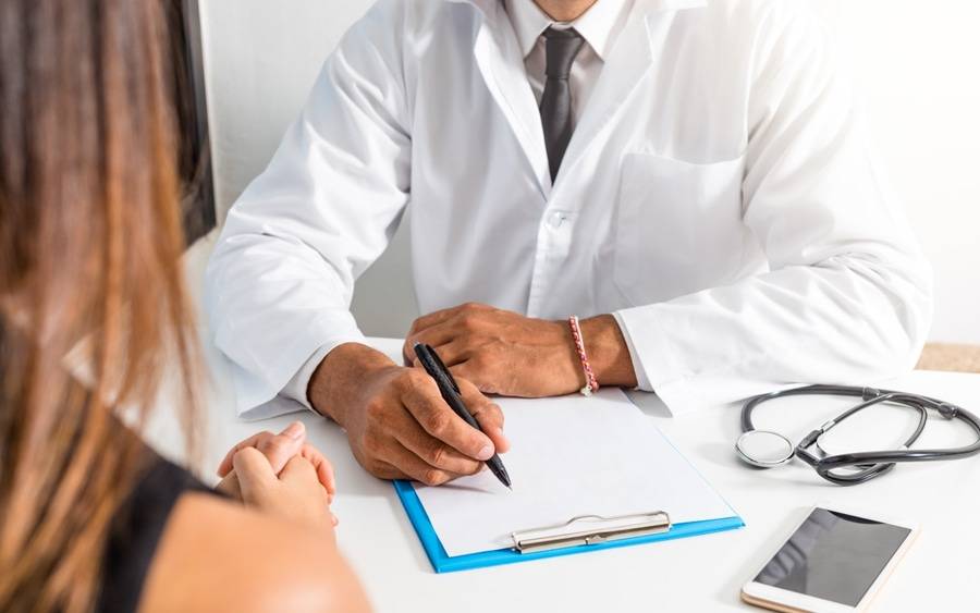 Doctor takes notes while discussing diagnosis with patient.