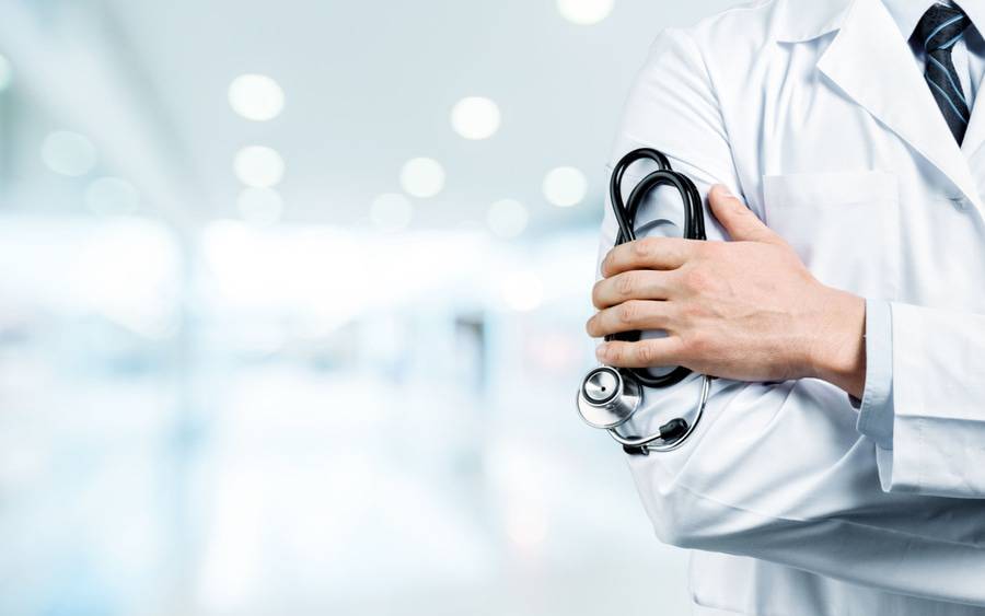 A doctor holding his stethoscope is featured, illustrating article on HMOs.