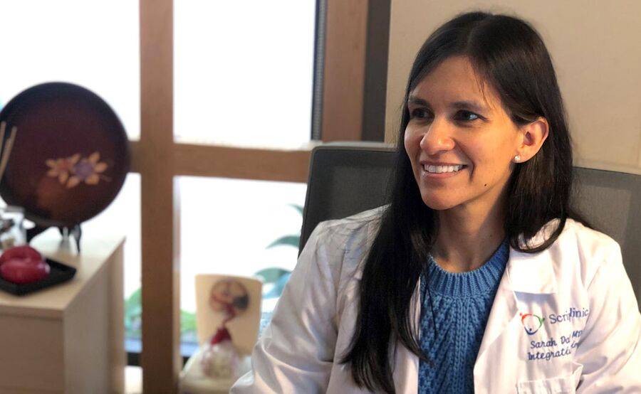 Dr. Sarah Dalhoumi, MD, Integrative Medicine, Scripps Clinic smiling sitting in a chair at Scripps Center for Integrative Medicine.