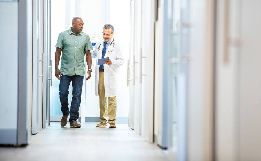 Dr. Imran Ahmed, Family Medicine, Scripps Coastal Medical Center physician walking down a hallway with a patient discussing their recent appointment.  