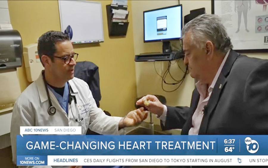 Scripps Clinic interventional cardiologist Curtiss Stinis, MD, shows patient John Rufo an aortic valve replacement device.