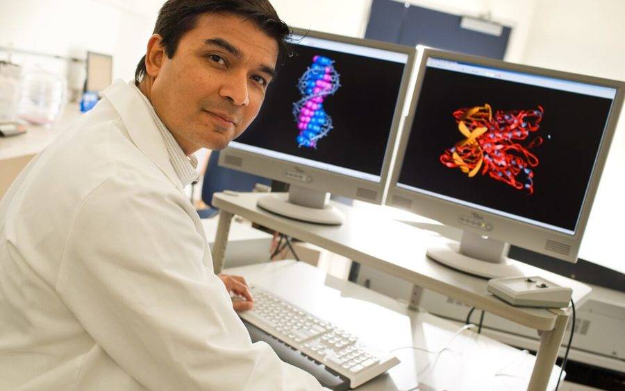 Dr. Darren D'Lima sits in front of two computer monitors in his lab.