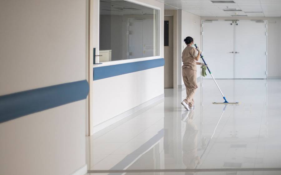 A hospital environmental services worker mops the floor.
