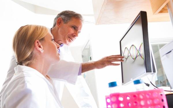 Two Scripps doctors view a strand of DNA on a computer monitor.