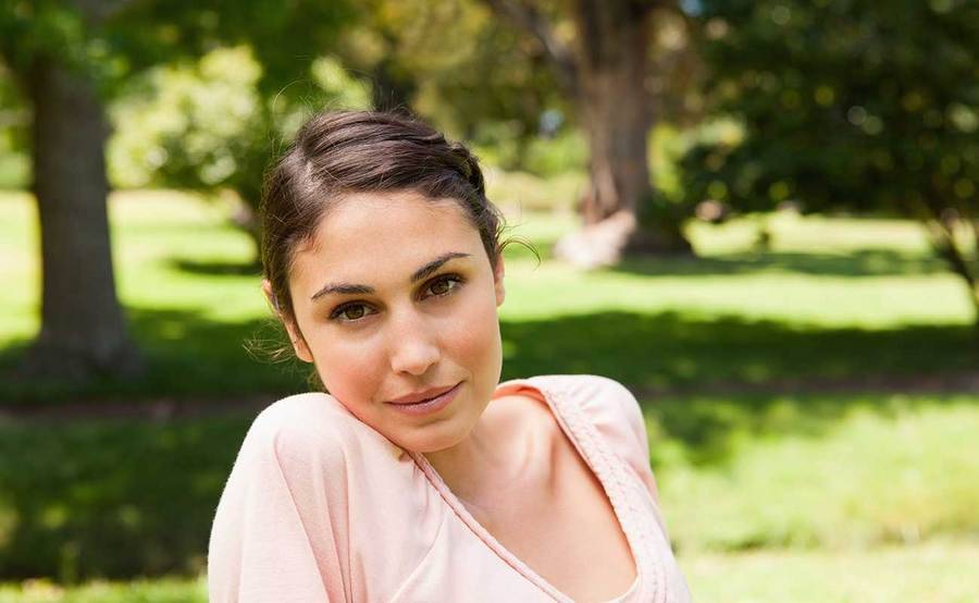 A confident young woman in a park represents the full life that can be led after Ewing sarcoma treatment.