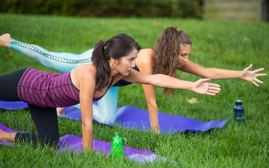 Two women workout by stretching.