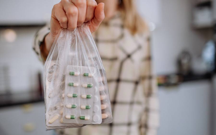 A woman holds a bag with expired medication to be discarded properly.