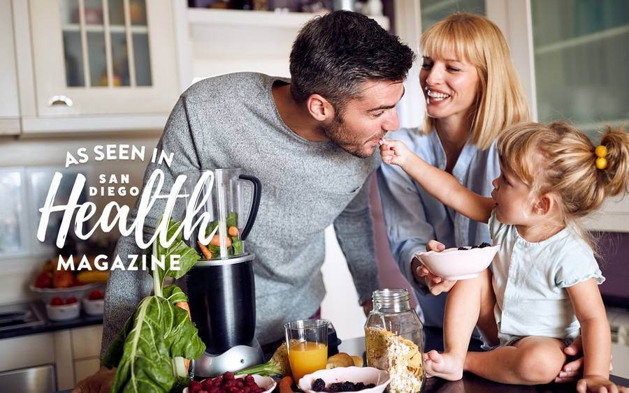 A father, mother and child all cooking together in the kitchen, illustrating how a family can stay healthy at home.