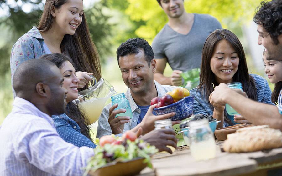 A family is having fun together and smiling at an outdoor picnic, illustrating outdoor activities where you would need to protect your skin.