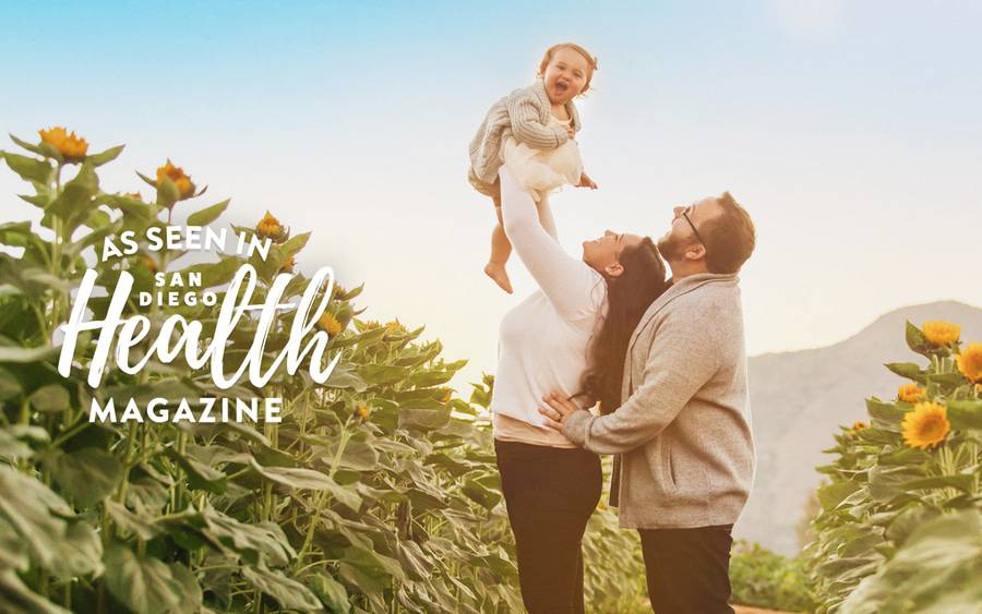 Annaliessa Newman-Wise stands with her husband and baby in a field of sunflowers, joyfully celebrating that she is cancer-free after treatment at Scripps.