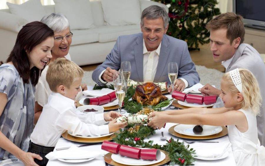 Family, including grandparents and grandchildren, gather around the dinner table for a healthy holiday meal.