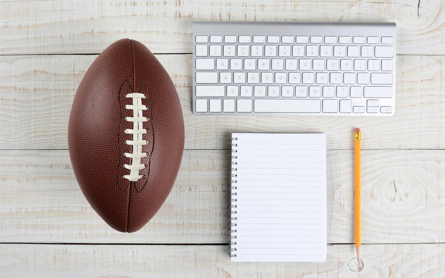 A football, computer keyboard, pencil and paper are symbols of fantasy football.