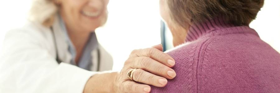A physician smiles while placing her hand on a patient’s shoulder, representing the compassion women can expect from urinary incontinence treatment at Scripps.