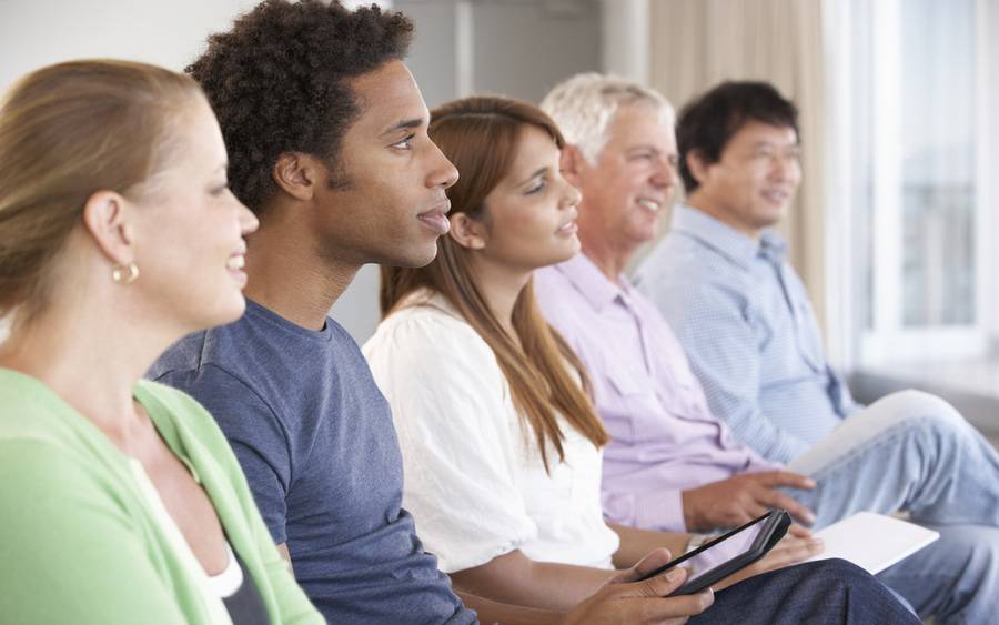 A group of adults sit in a room, listening to their group medical appointment.