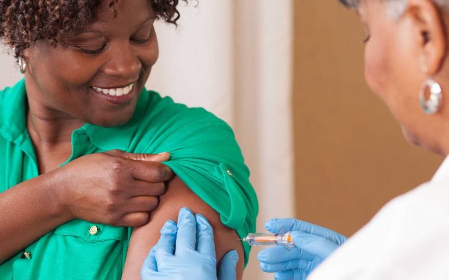 A woman receiving her flu shot by her provider.