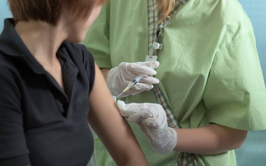 A physician administers a flu shot to a woman as a way to fight rising cases of the flu.
