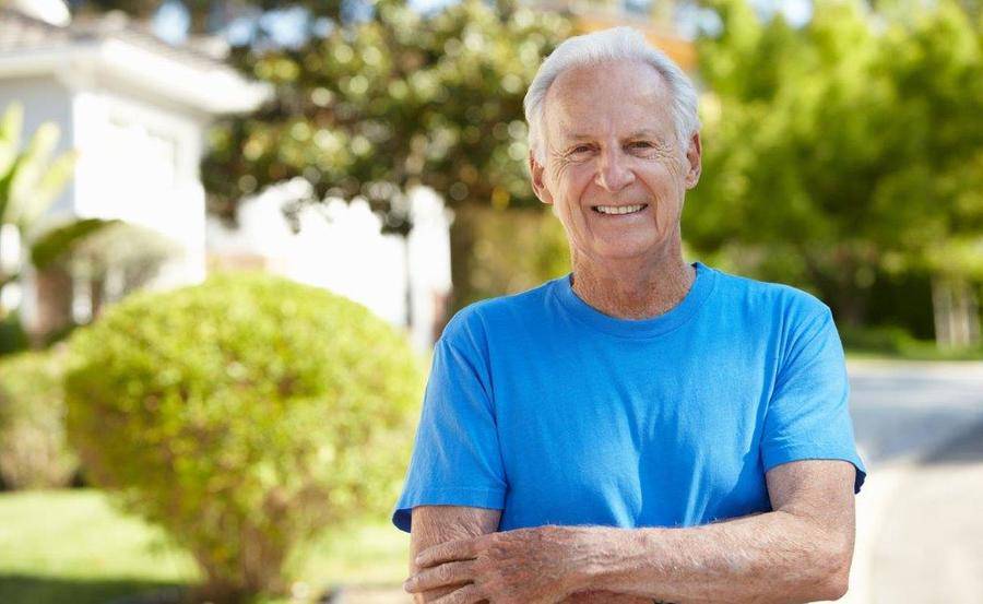 A man standing in front of home, smiling