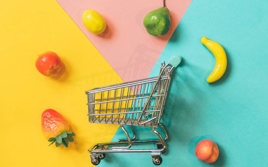 A shopping car surrounded by healthy organic produce.