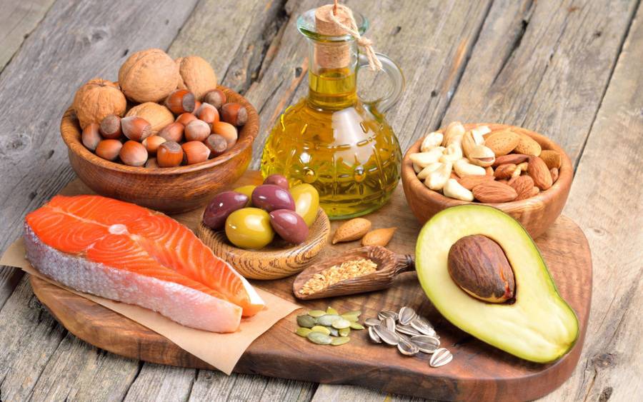 A spread of foods with healthy fats, including fish, avocado, nuts, legumes and oils.