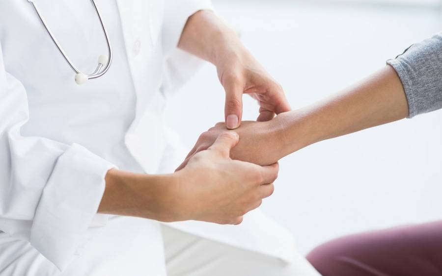 A health care provider checks a patient's hand for ganglion cyst.