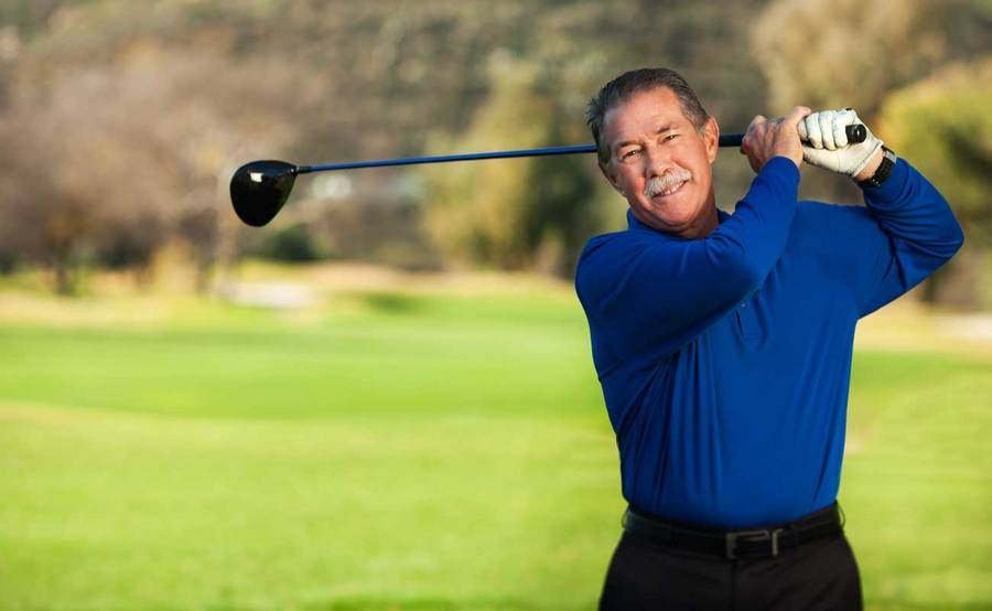 A smiling Gary Collins swings a golf club after a successful hip replacement at Scripps Health.