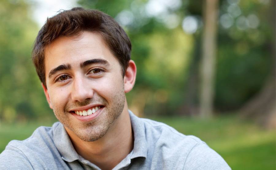 A younger man smiling outdoors