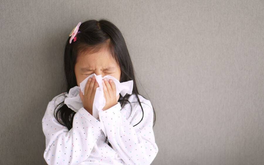 A girl with allergies sneezes.