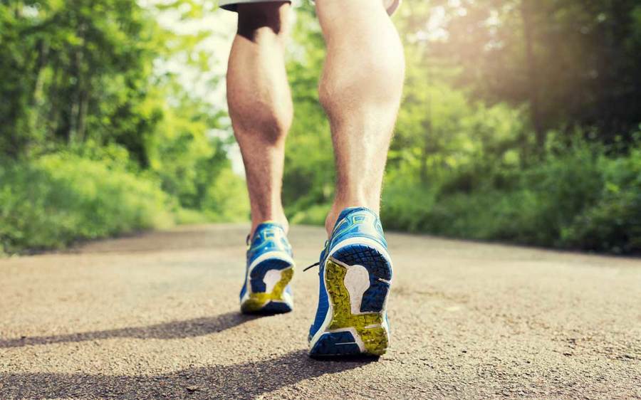 Close up image of man running on a trail in an outdoor setting