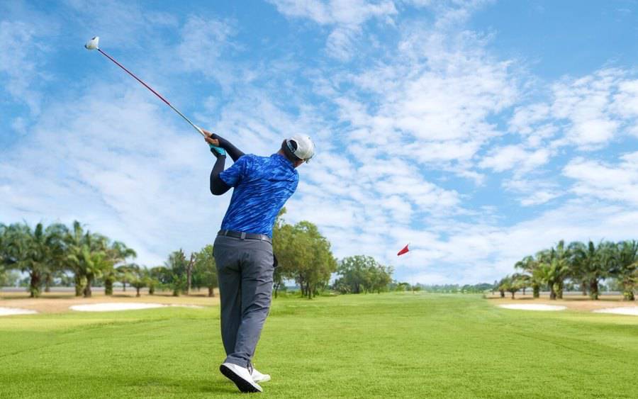 Golf player swings away.