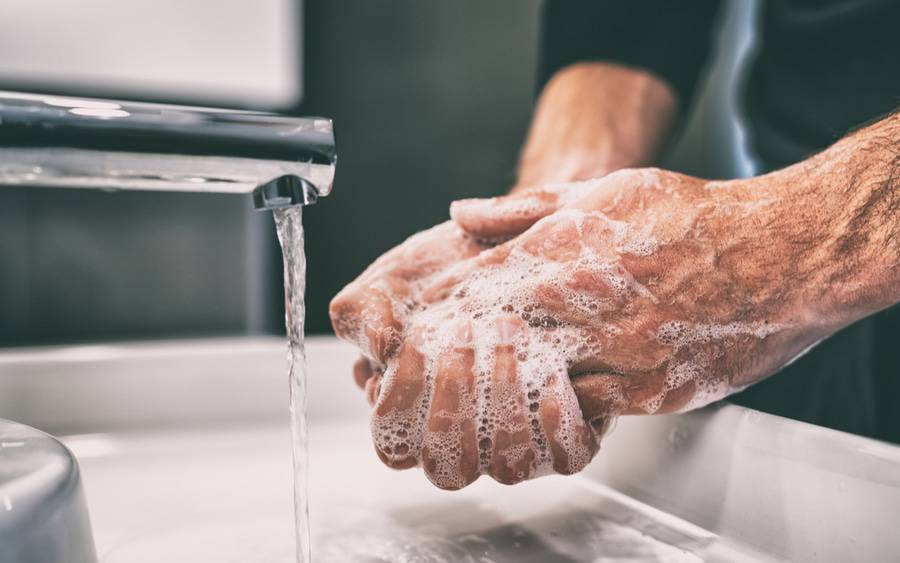 A male washing his hands at a sink.