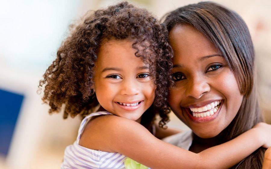 African-American mother holding her daughter, with no trace of stress on her smiling face.