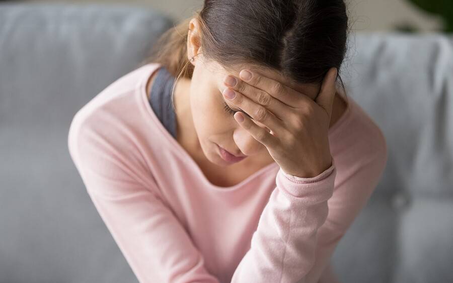 A young woman rubs her forehead to help soothe her headache.