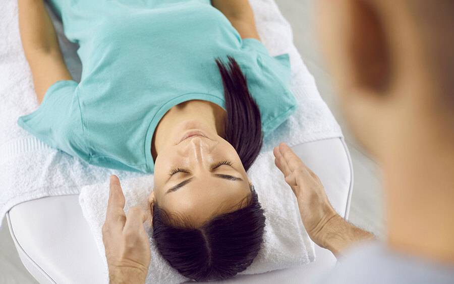 woman on back with practicioner hands near ears