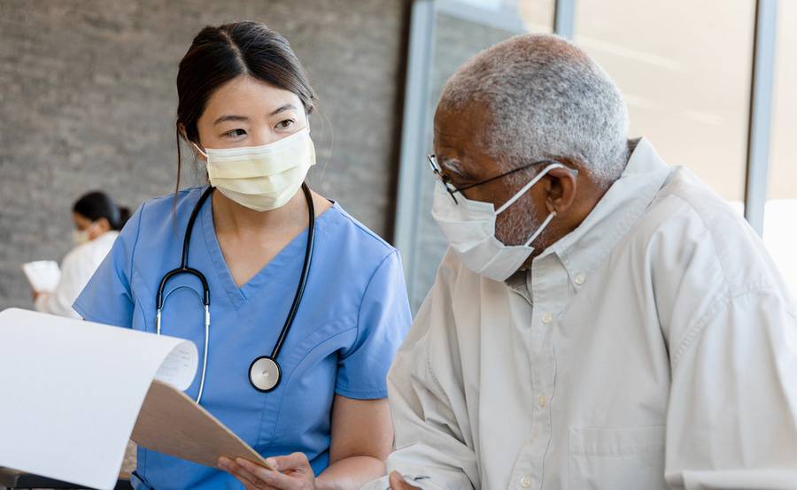A health care provider discussing a plan with an older ,ale patient, illustrating a Medicare Annual Wellness Visit.